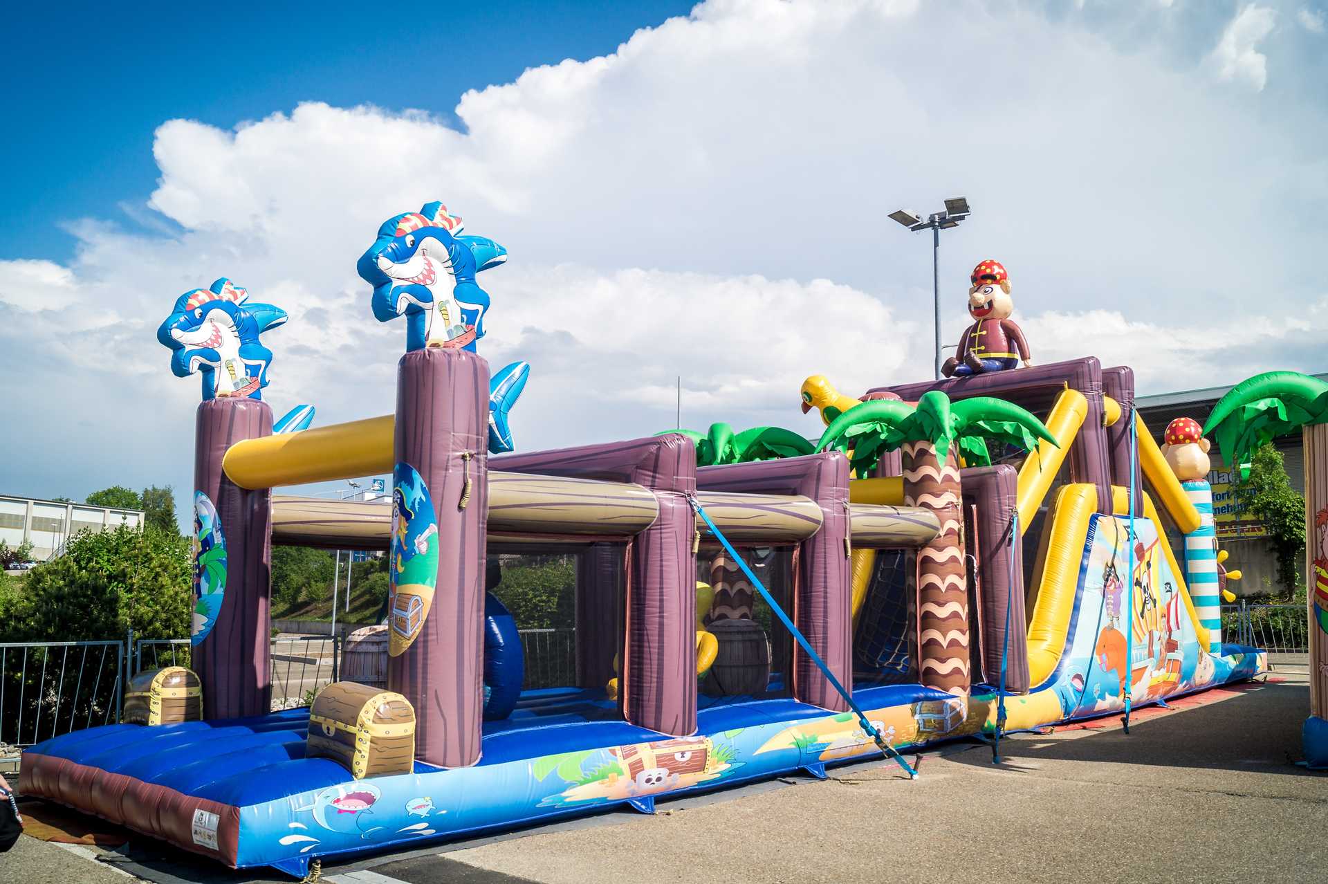 Piraten-Hüpfburg mit Rutsche, Palmen und Hai-Figuren im Außenbereich des Hofmeister Funparks